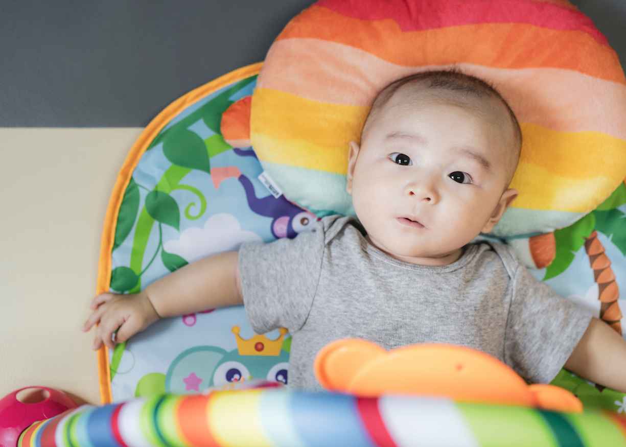 A baby playing with toys on a soft play mat